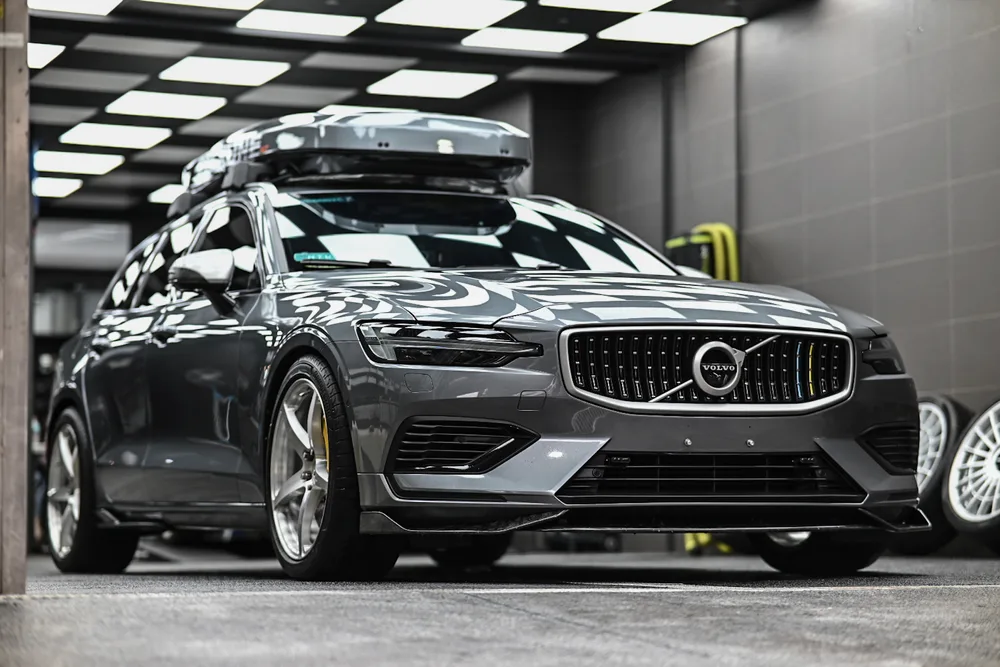 灰色 Volvo V60 旅行車完工停於施工區,車頂行李箱與車身漆面倒影清晰,誠美車體美容