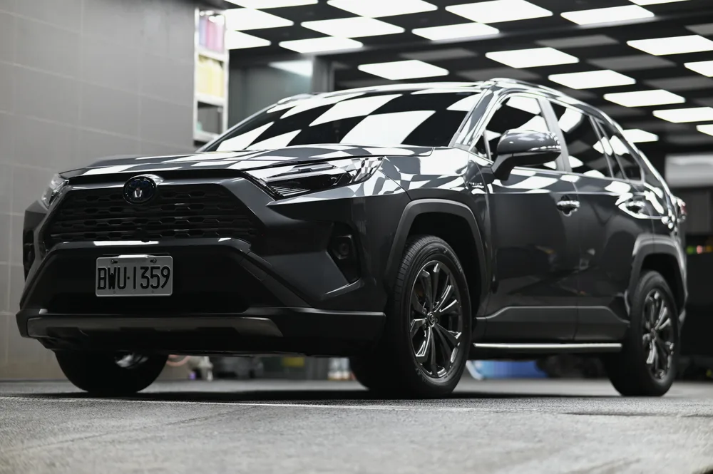 灰色 Toyota RAV4 Hybrid 完成精緻打蠟後停於格紋施工區,車側全景鈑面映出天花板格紋,誠美車體美容