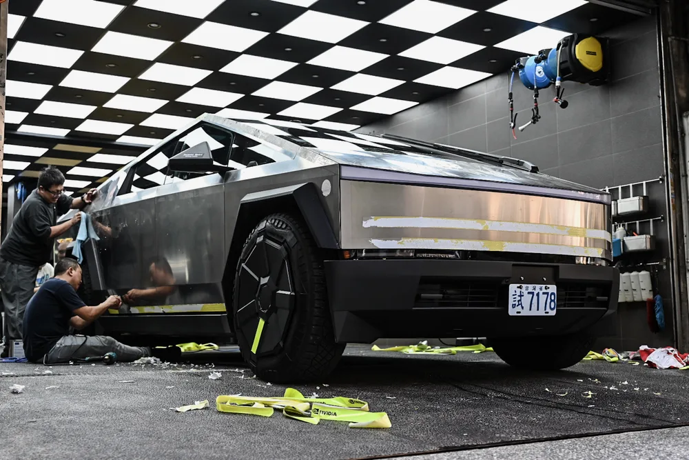 兩位技師合力清除 Tesla Cybertruck 車側殘膠,不鏽鋼板件大面積回復原色,誠美車體美容