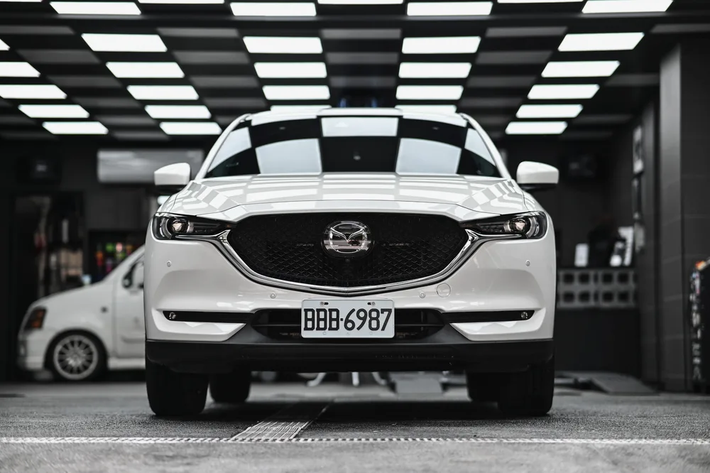 打蠟完工的白色 Mazda CX-5 停在施工區,車頭在燈條下呈現柔亮光澤,誠美車體美容