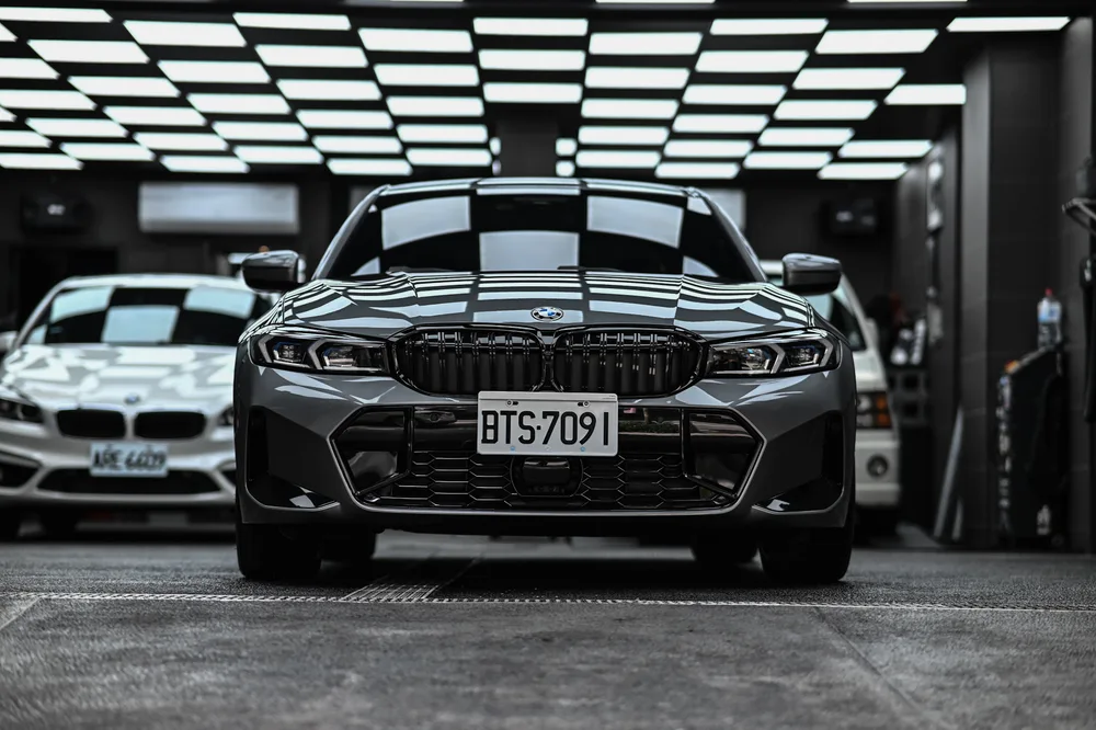 BMW 330i M Sport 灰色車身完成打蠟後的車頭正面,雙腎形水箱罩與引擎蓋線條映出廠內燈條|誠美車體美容