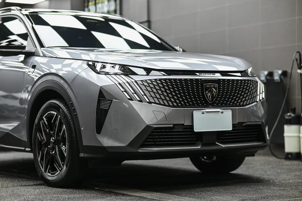 銀灰色 Peugeot 5008 完成車頭迎風面透明保護膜包覆後,停於施工棚內的左前四十五度全車樣貌,誠美車體美容