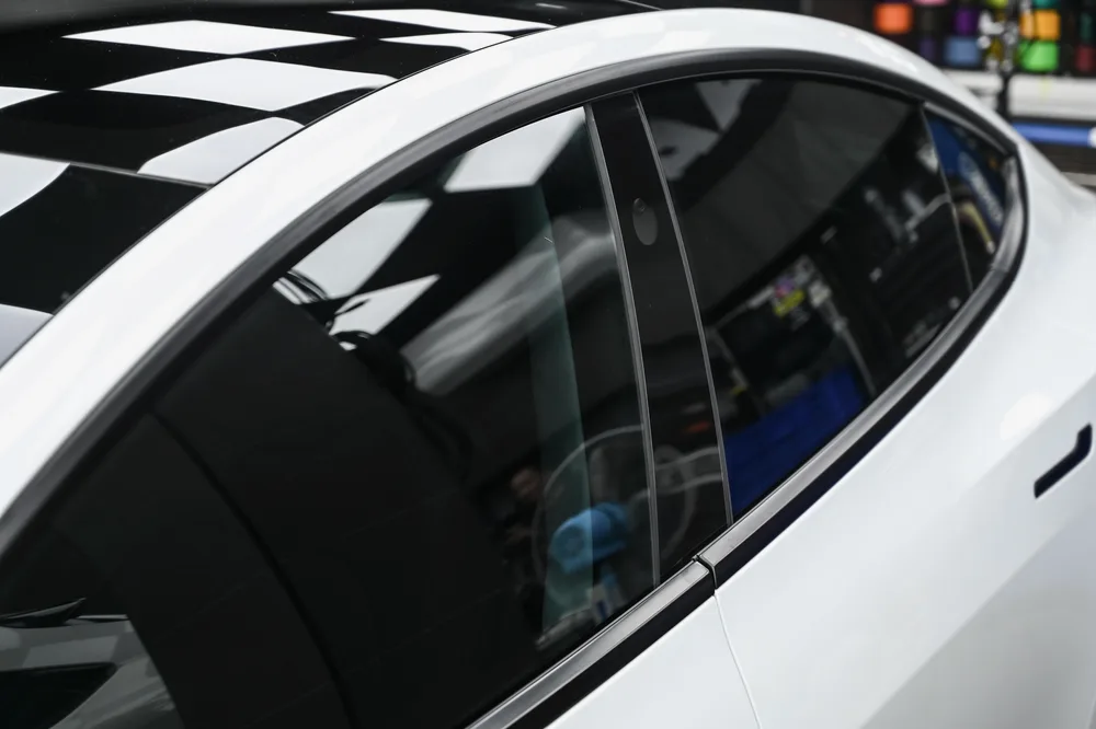 白色 Tesla Model 3 完成全車隔熱紙貼附,於施工棚內呈現的側面車窗色澤,誠美車體美容