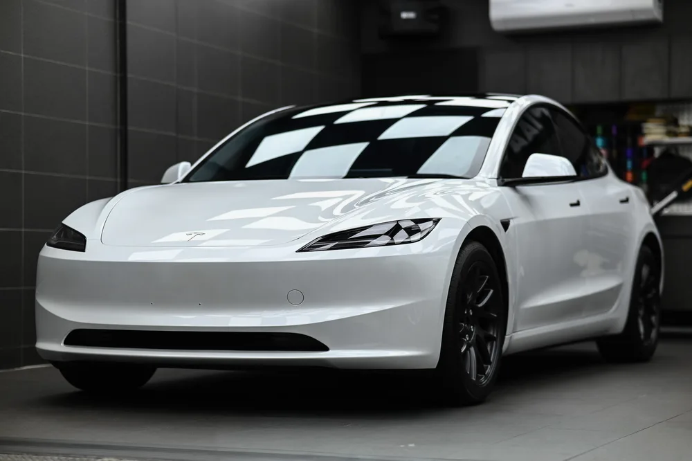 白色 Tesla Model 3 完成拋光與雙層鍍膜後,於施工棚內呈現的左前四十五度車身光澤,誠美車體美容