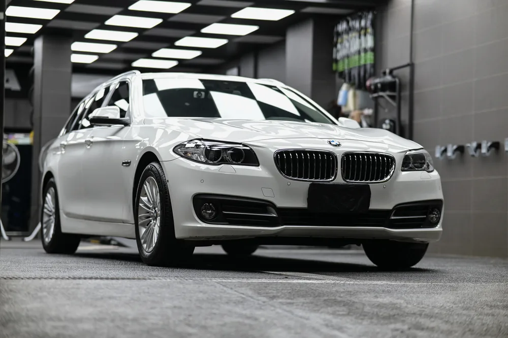 打蠟完工的白色 BMW 520i 停放於施工區,車頭與車側呈現柔和光澤,誠美車體美容