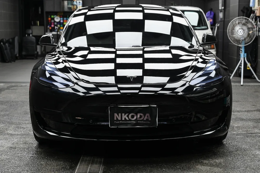 黑色 Tesla Model 3 完成精緻漆面護理後,停於施工棚內的車頭正面光澤,誠美車體美容