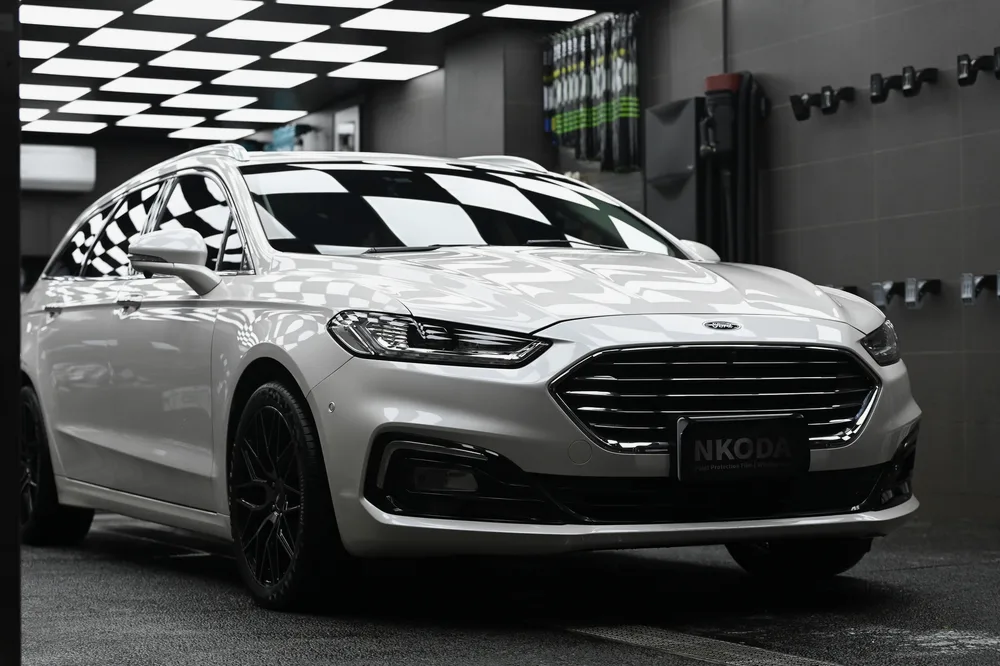 白色 Ford Mondeo 旅行車完工後停在棚內,車頭 45 度角車身線條與漆面光澤完整呈現|誠美車體美容